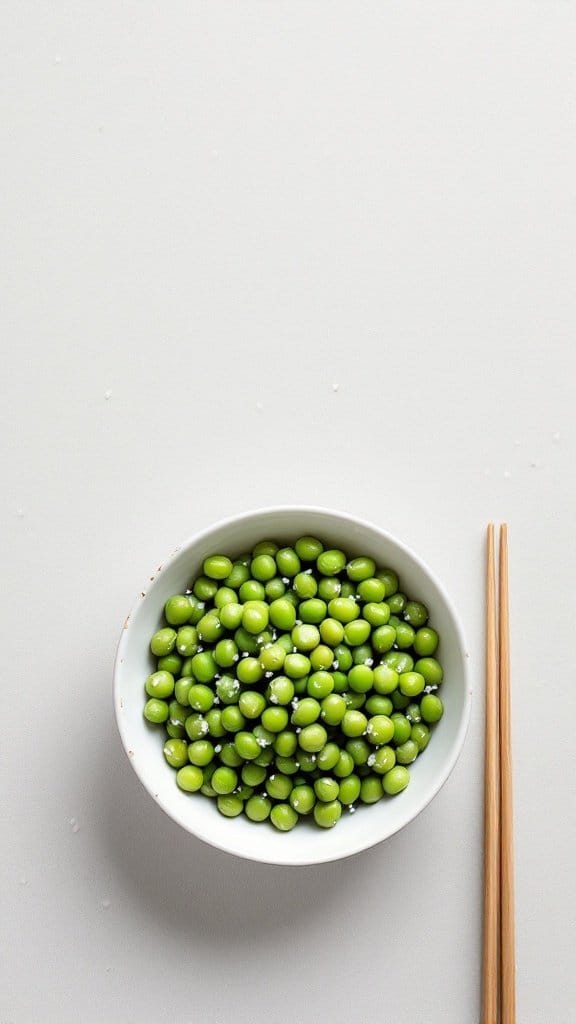 A bowl of edamame sprinkled with sea salt, with chopsticks beside it.